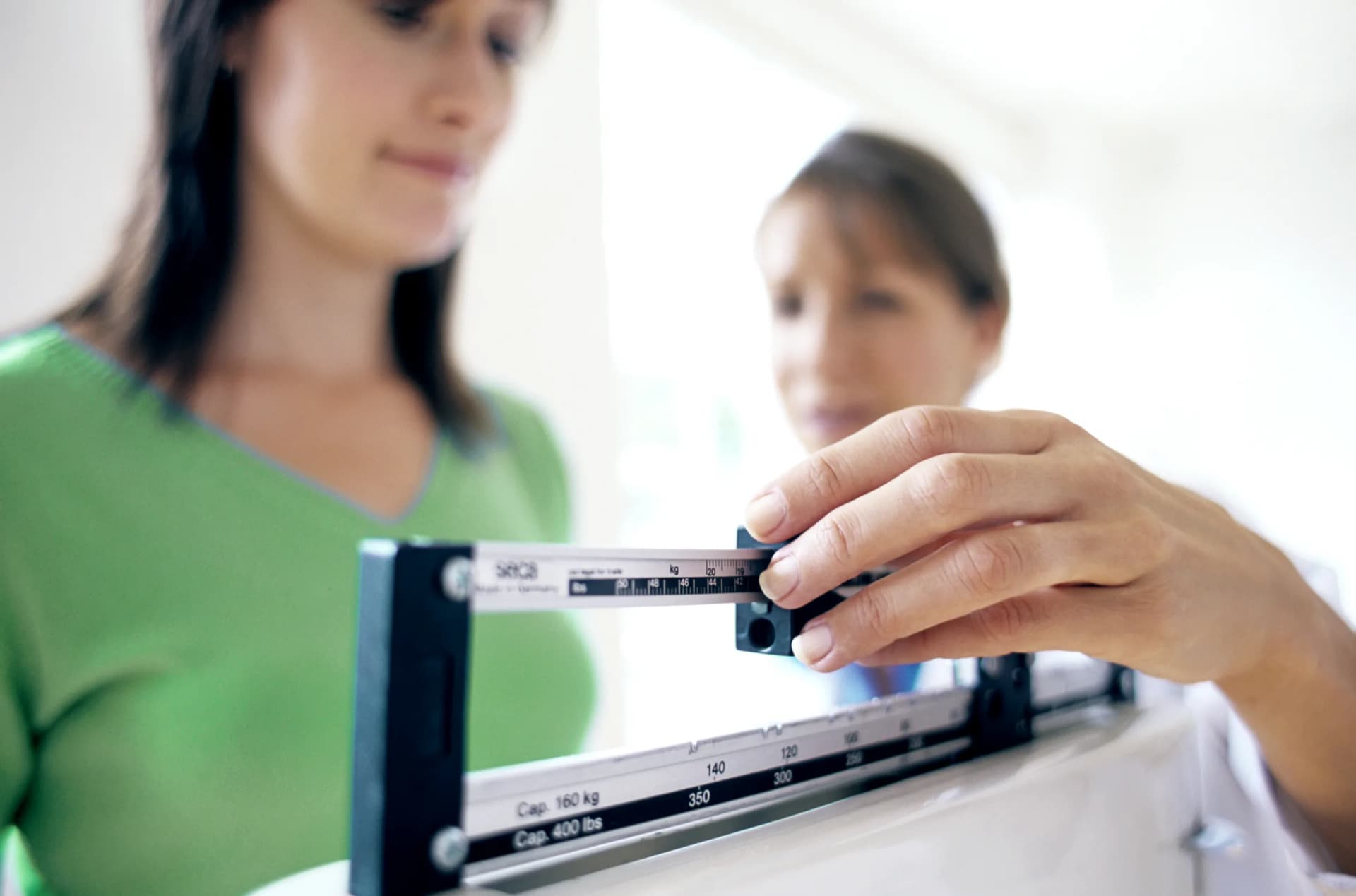 Clinician adjusting a beam scale while a patient stands on it